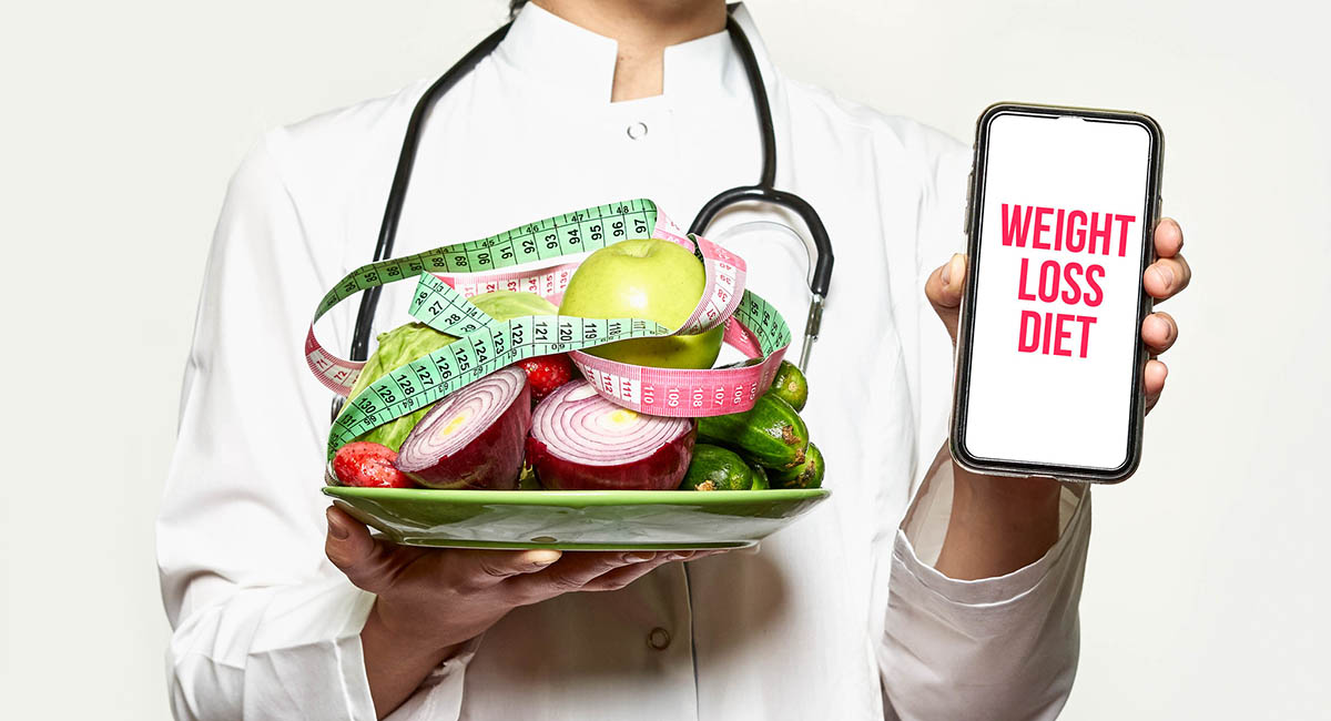 doctor holding plate of vegetables with measuring tape and phone that says WEIGHT LOSS DIET