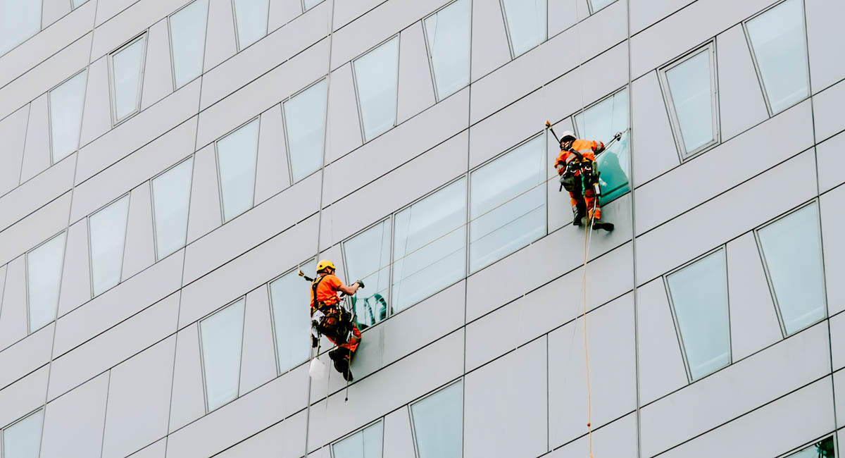 two men suspended on large modern building to wash windows